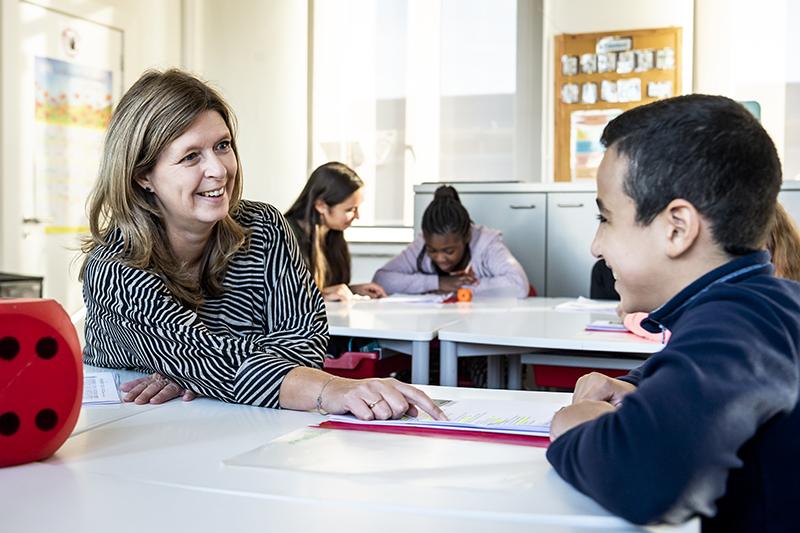 leerkracht en leerling in gesprek in een school voor stedelijk buitengewoon lager onderwijs